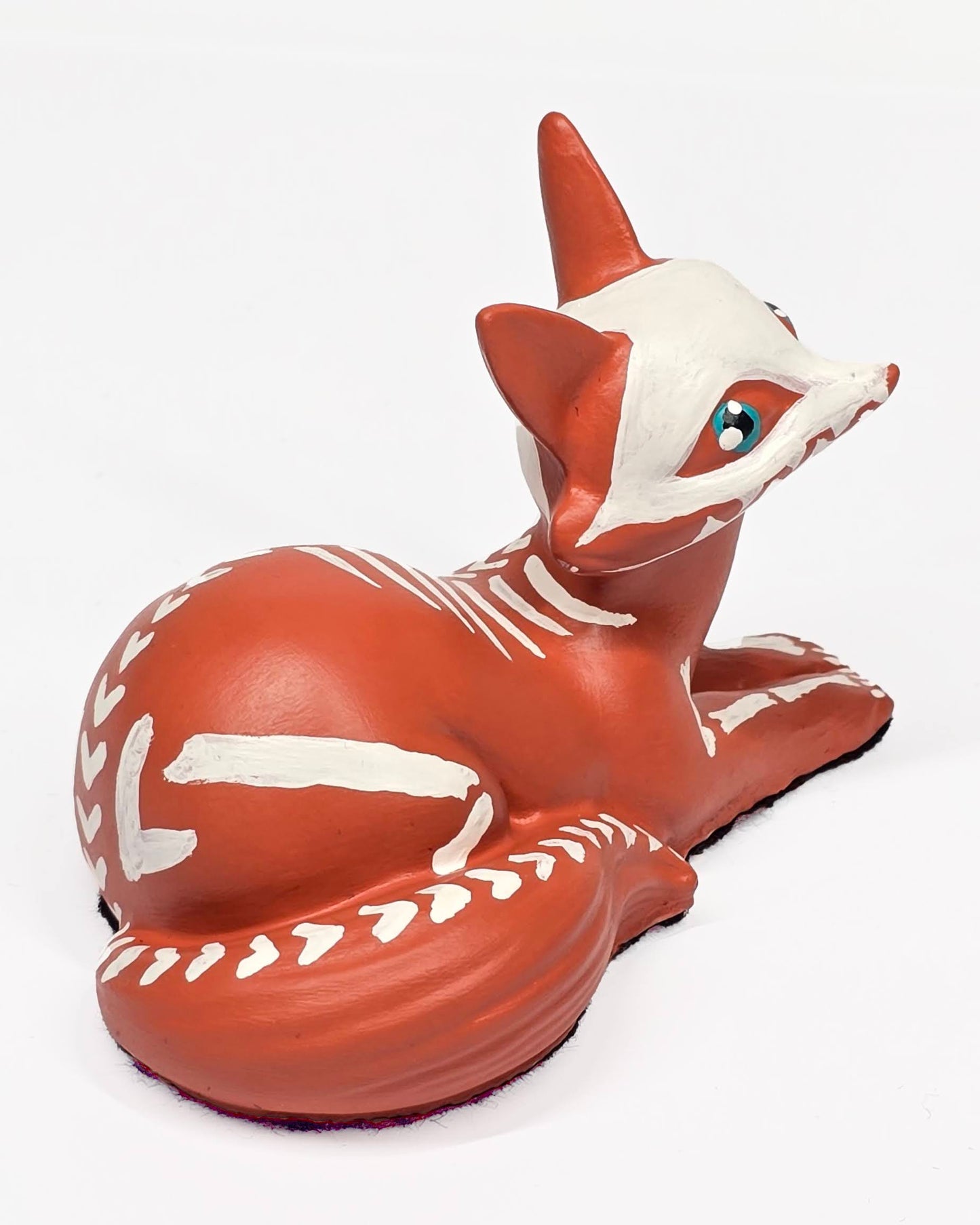 Terracotta-colored fox figurine with white skeleton hand painted, on a white background