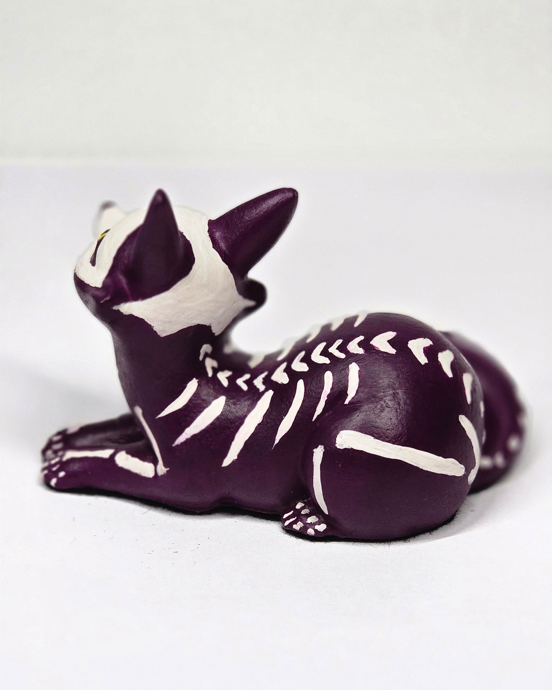 Purple and white skeleton puppy figurine on a light gray background