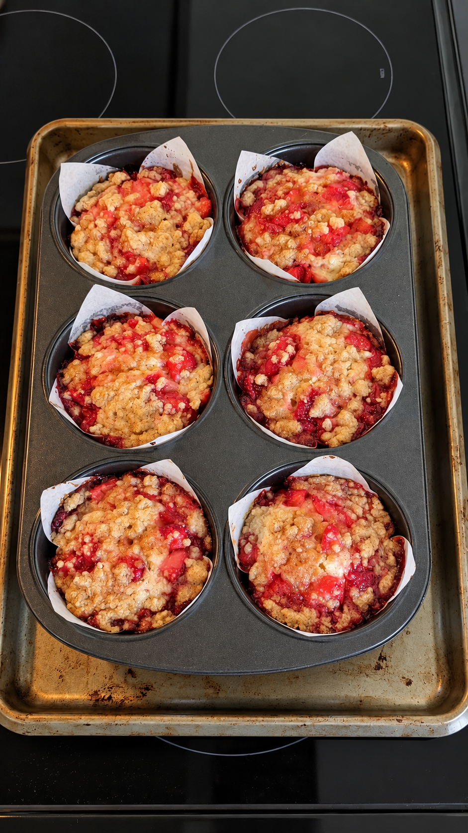 Six strawberry crumble jumbo muffins in the baking tin on Jessie's stovetop